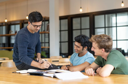 Serious teacher checking assignment of two students Serious teacher checking assignment of two students